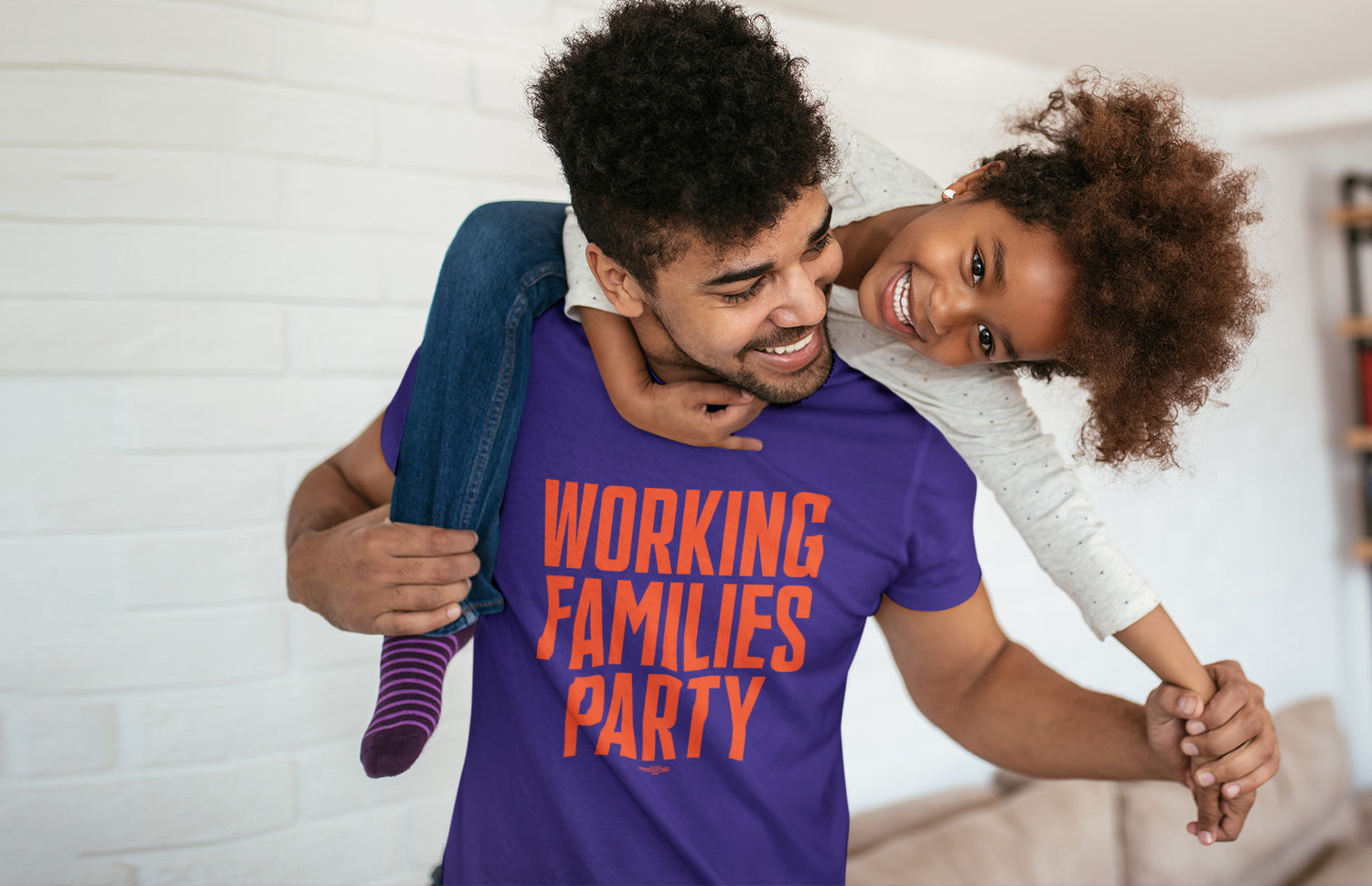 man in working families party t-shirt holding his daughter